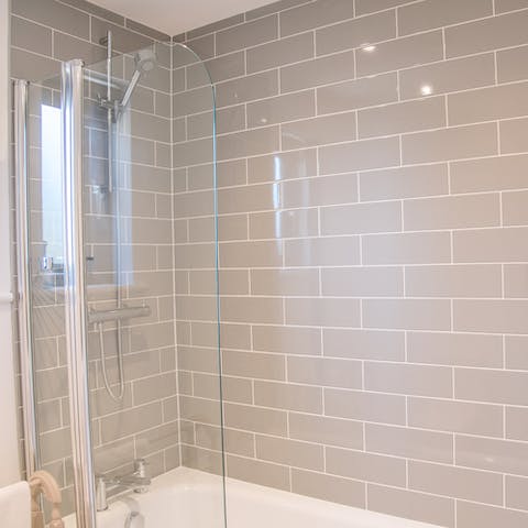 Lie back in the home's bathtub underneath sleek grey subway tiling