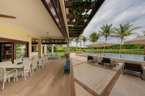 Dine alfresco steps from the pool beneath a vine-draped pergola