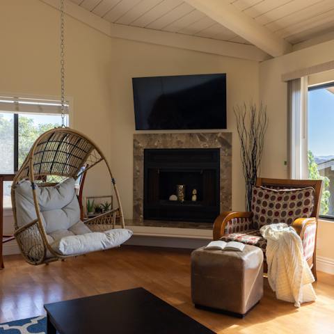 Get cosy in the egg chair or armchair with a good book by the decorative fireplace