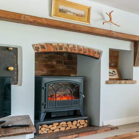 Cosy up by the fireplace in the living room with a movie on the TV