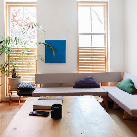 Enjoy a good book in the refreshing living space with playful cloud-shaped cushions and wood-slat blinds