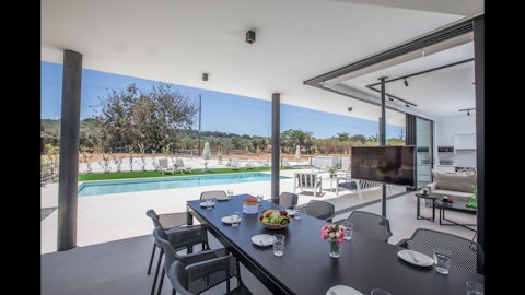 Dine poolside under a shaded terrace with countryside views