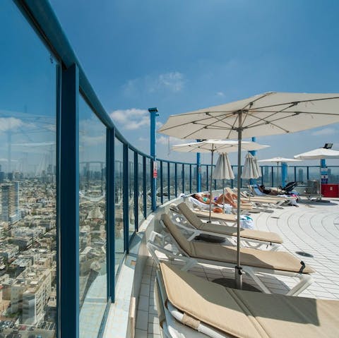 Sunbathe by the pool on the beds with an incredible view of the city