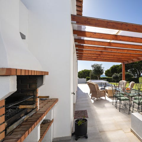 Light the stone grill for a barbecue feast beneath the pergola