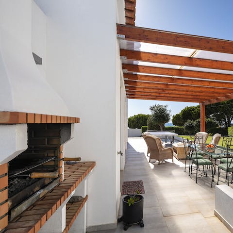 Light the stone grill for a barbecue feast beneath the pergola