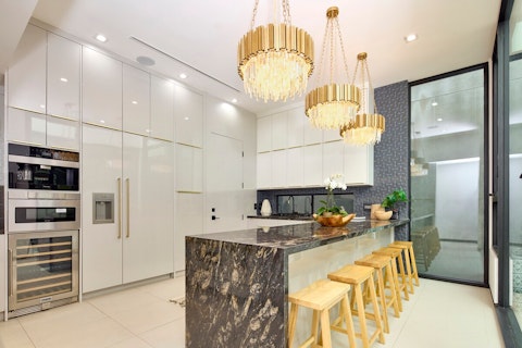Cook beneath gold chandeliers at a dramatic stone island
