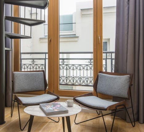 Relax on the designer chairs next to huge French windows
