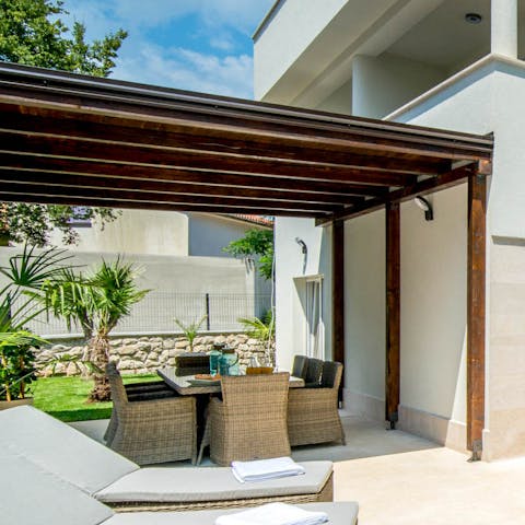 Gather around for fresh barbecue dinners, drinks, and games beneath the wooden pergola