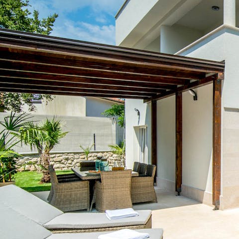 Gather around for fresh barbecue dinners, drinks, and games beneath the wooden pergola