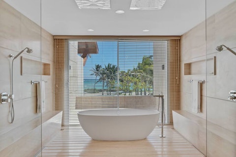 Unwind in the spa-like bathroom with palm-fringed sea views