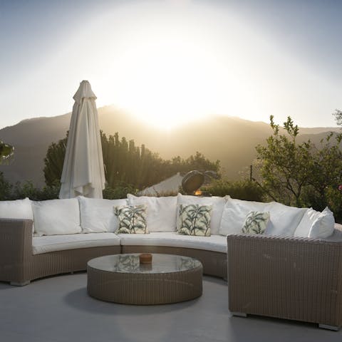 Settle on the white cushions to watch the sun set beneath the hills
