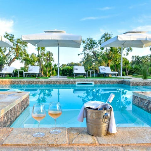 Indulge in a bottle of primitivo wine while dipping your feet in the swimming pool