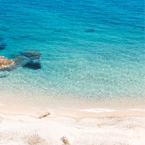 Paddle the shallow shores of Psarou beach, a short drive away