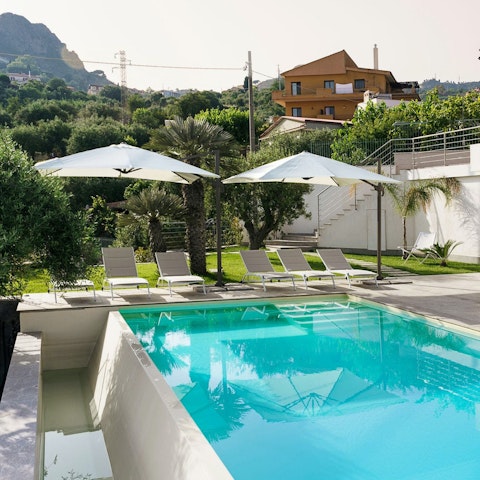 Stretch out by the pool, framed by soaring Sicilian mountains
