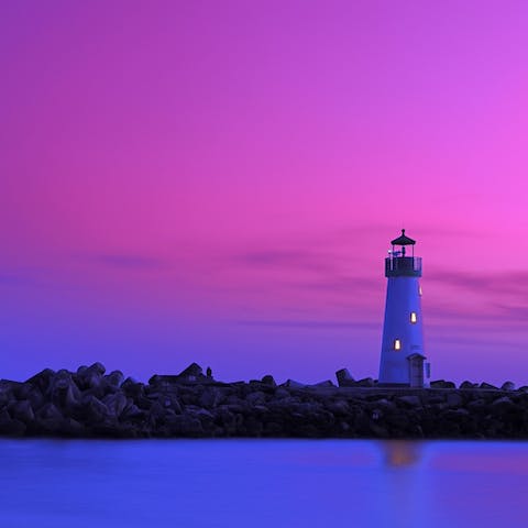 Walk along Field State Beach at sunset, keeping the lighthouse within view