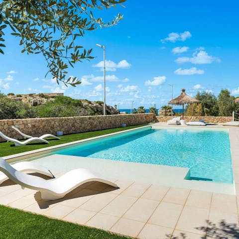 Sunbathe by the pool with views of the coastline