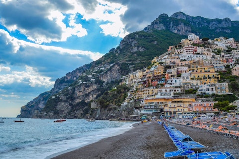 Relax on Positano's iconic beach framed by pastel clifftop houses, a sixteen-minute walk