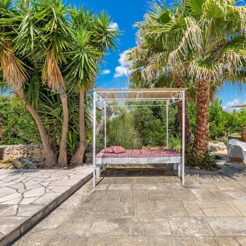 Relax on the day bed, soaking up the sun as the palm trees sway beside you