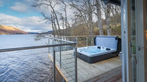 Soak in the hot tub overlooking the loch and hills beyond