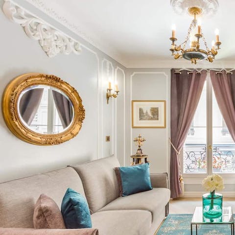 Relax in a refined and sophisticated living space with ornate mirrors, chandeliers and white mouldings