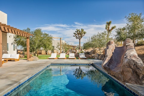 Slide into the pool framed by desert boulders and Joshua trees