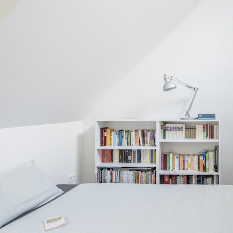 Cosy up in the minimalist bedroom with one of the many books from the shelves