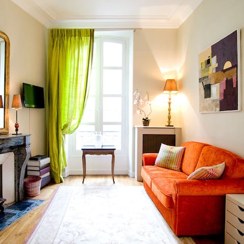 Unwind on the vivid orange sofa in a living area full of natural light