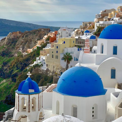 Explore Santorini's charming villages, dotted with blue domes