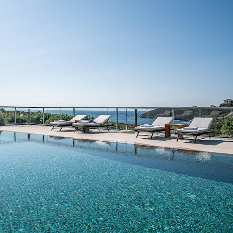 Lounge around the swimming pool with views of the Mediterranean Sea in the background