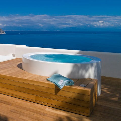 Enjoy a soak in the hot tub while admiring the sea views