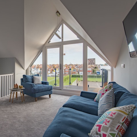 Relax with a glass of wine on the plush sofas after a long day of exploring, watching the sun go down through the floor-to-ceiling window