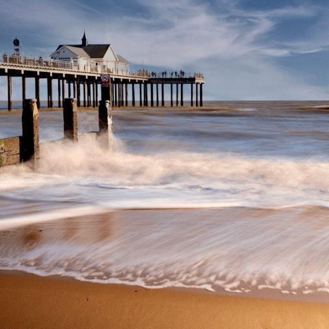 Stroll Southwold Beach's golden sands lined with beach huts, a twenty-minute drive