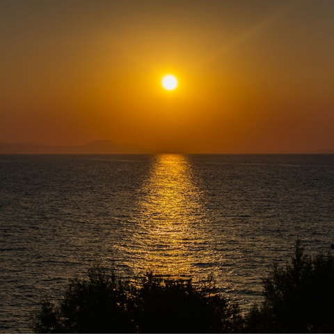Watch the sunset from Paralia Panormos beach, a six-minute drive