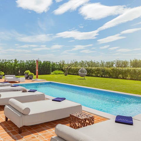 Sunbathe on one of the luxury beds by the swimming pool