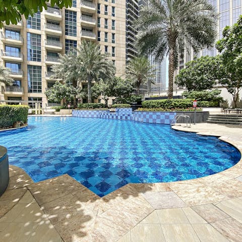 Cool off with a refreshing dip in the communal outdoor pool surrounded by luscious palm trees