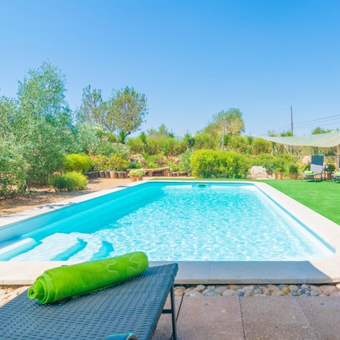 The property is surrounded by lush gardens and has a large pool.