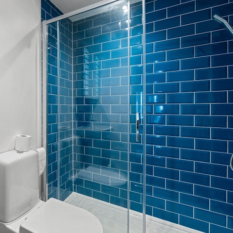 Feel serene after calming walk-in shower in the blue-tiled bathroom