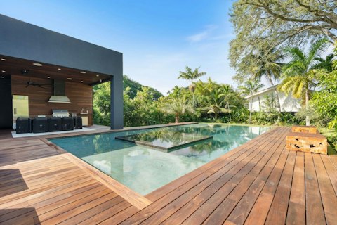 Grill alfresco beside a gleaming pool fringed by palms