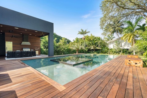 Grill alfresco beside a gleaming pool fringed by palms