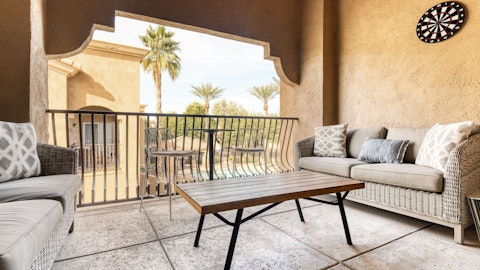 Unwind on the balcony terrace overlooking palm trees and the shared pool