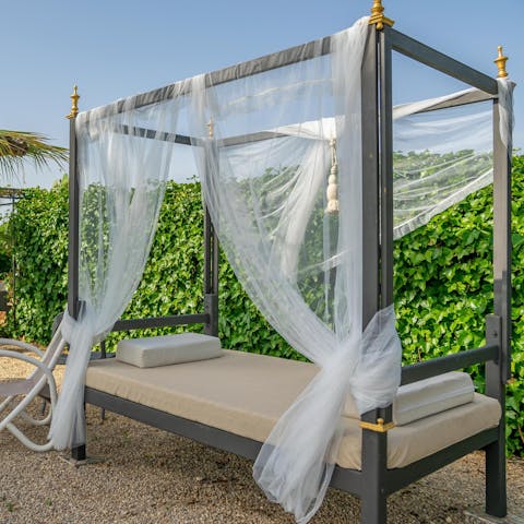 Lie back on the elegant, four-poster sun lounger with a cocktail