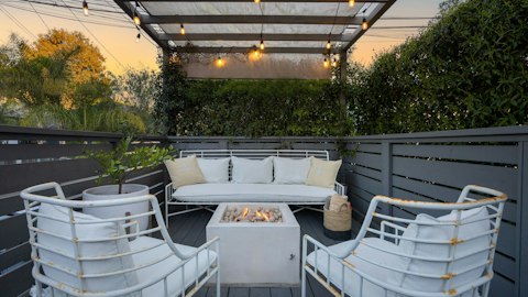 Gather around the fire pit beneath string lights at dusk