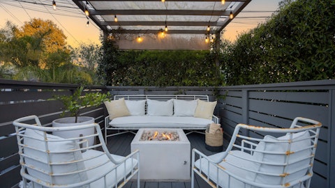 Gather around the fire pit beneath string lights at dusk