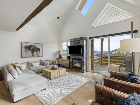 Sink into the sofa beside a glowing fireplace with mountain views