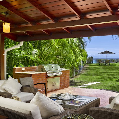 Sip tropical cocktails at the outdoor lounge and kitchen area with a glistening sea view