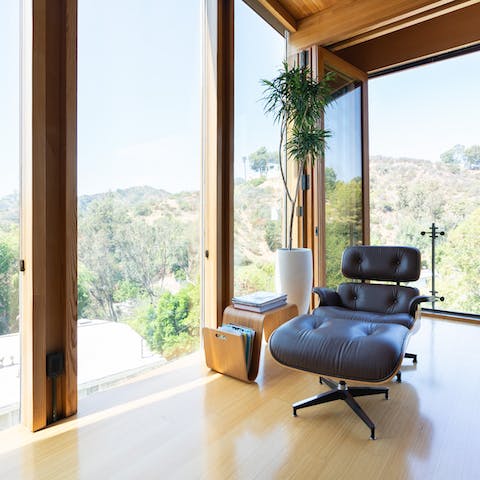 Relax in the elegant Eames chair by the floor-to-ceiling glass walls