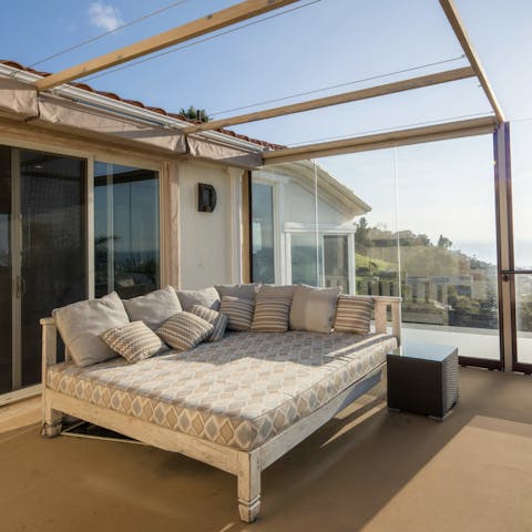 Recline on the day bed as the sun sets over the ocean