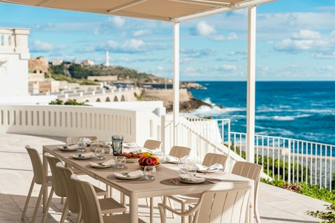 Dine alfresco with crashing waves and a lighthouse on the horizon