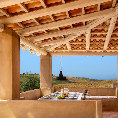 Gather around the dining table beneath the pergola for a relaxed evening of good food and wine, while the low-hanging light fixture sets the ambience