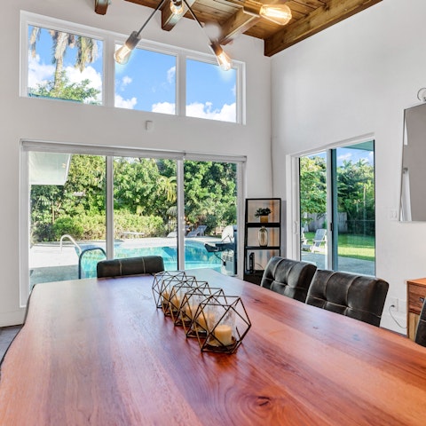 Eat at the grand dining table overlooking the luscious garden and pool